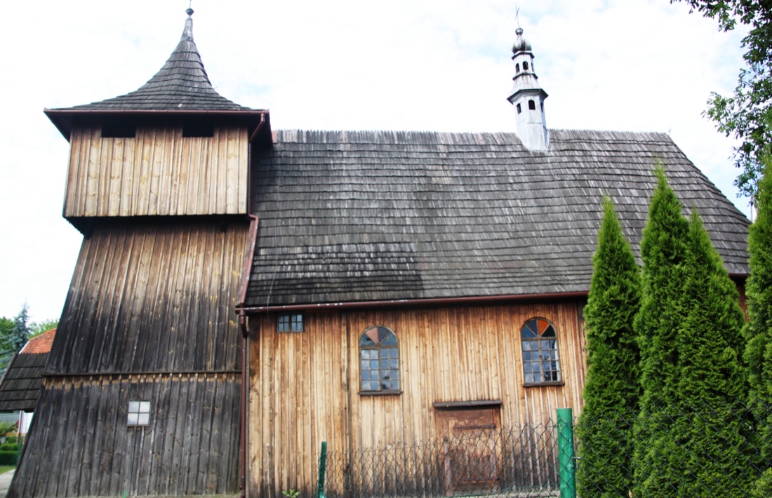 Widok od boku — z lewej wieża z nadwieszoną izbicą, dalej nawa pod wspólnym gontowym dachem i sześcioboczna wieżyczka na sygnaturkę.